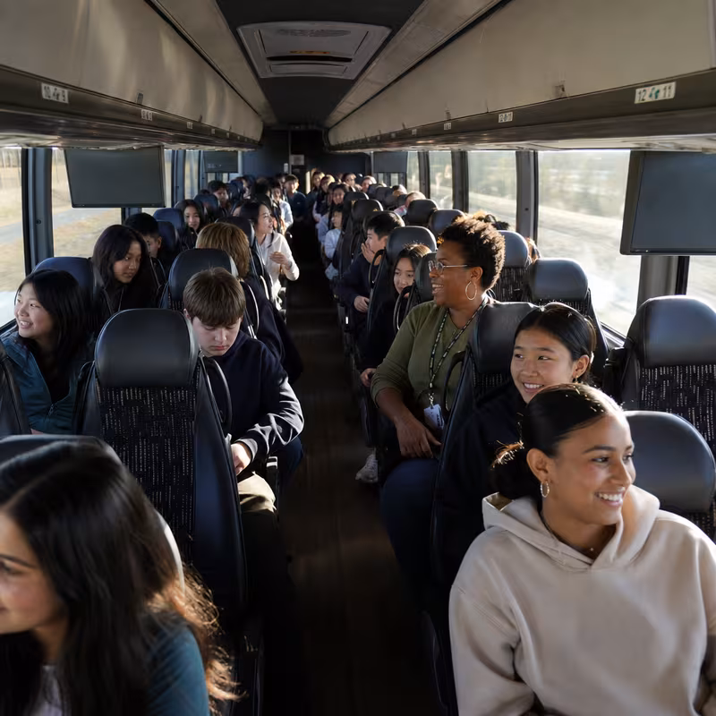 Group boarding a white charter bus for School Transportation transportation in Augusta
