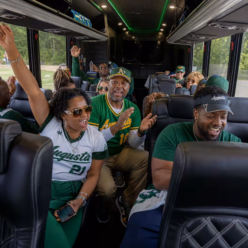 Group boarding a white charter bus for Sporting Event Transportation transportation in Augusta